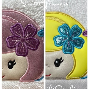 May include: Two embroidered designs of a girl with a flower in her hair. The girl on the left has pink hair and a purple flower. The girl on the right has yellow hair and a blue flower. The text "Sweet Flowers" is above the designs and the text "Stacie's Quilt Studio" is below the designs.
