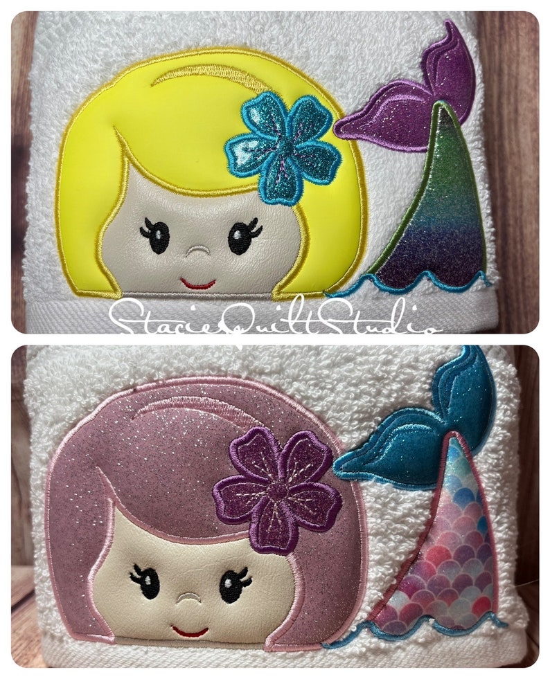 May include: Two embroidered towels with a mermaid design. The top towel features a yellow-haired mermaid with a blue flower and a purple tail. The bottom towel features a pink-haired mermaid with a purple flower and a blue tail with pink scales.