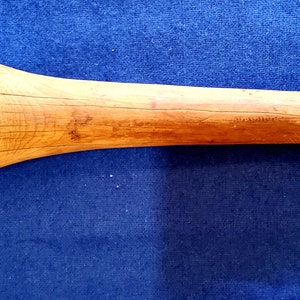 May include: A wooden mallet with a rounded head and a long handle. The handle has a small hole at the end with a frayed cord attached.
