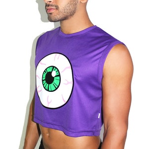 May include: Purple sleeveless crop top with a large white eye graphic with a green iris. The top has a cropped hemline.