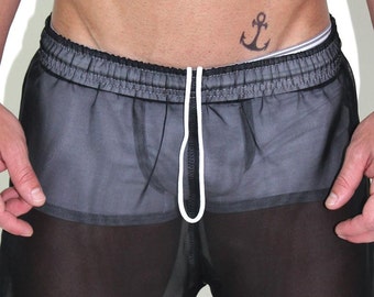 May include: Black sheer mesh shorts with a white drawstring. The shorts have a black elastic waistband and white stitching around the edges.