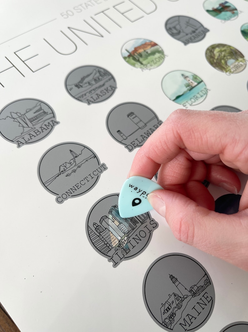 May include: A light blue guitar pick with the word "wayp" and a location icon is held over a gray circle labeled "ILLINOIS" on a white map. The map features illustrations of U.S. states, including "ALABAMA," "ALASKA," and "MAINE."