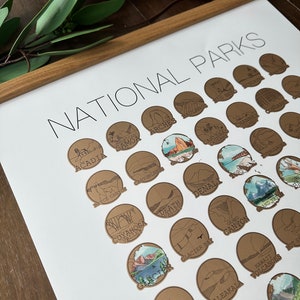 May include: A brown and white poster with the title "National Parks" and illustrations of different national parks in the United States. Each park is represented by a circle with a brown background and a black outline. The illustrations are simple and stylized, depicting iconic features of each park.
