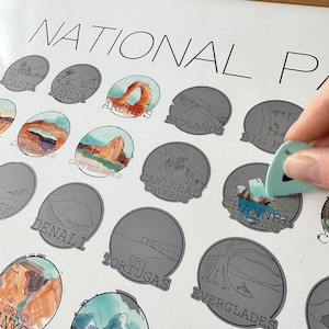 May include: A poster with a white background and the text "NATIONAL PARKS" at the top. The poster features a grid of illustrated national parks, each with a unique design and name. The parks include Acadia, American Samoa, Arches, Badlands, Big Bend, Canyonlands, Capitol Reef, Carlsbad Caverns, Channel Islands, Denali, Dry Tortugas, Everglades, Grand Canyon, and Grand Teton.