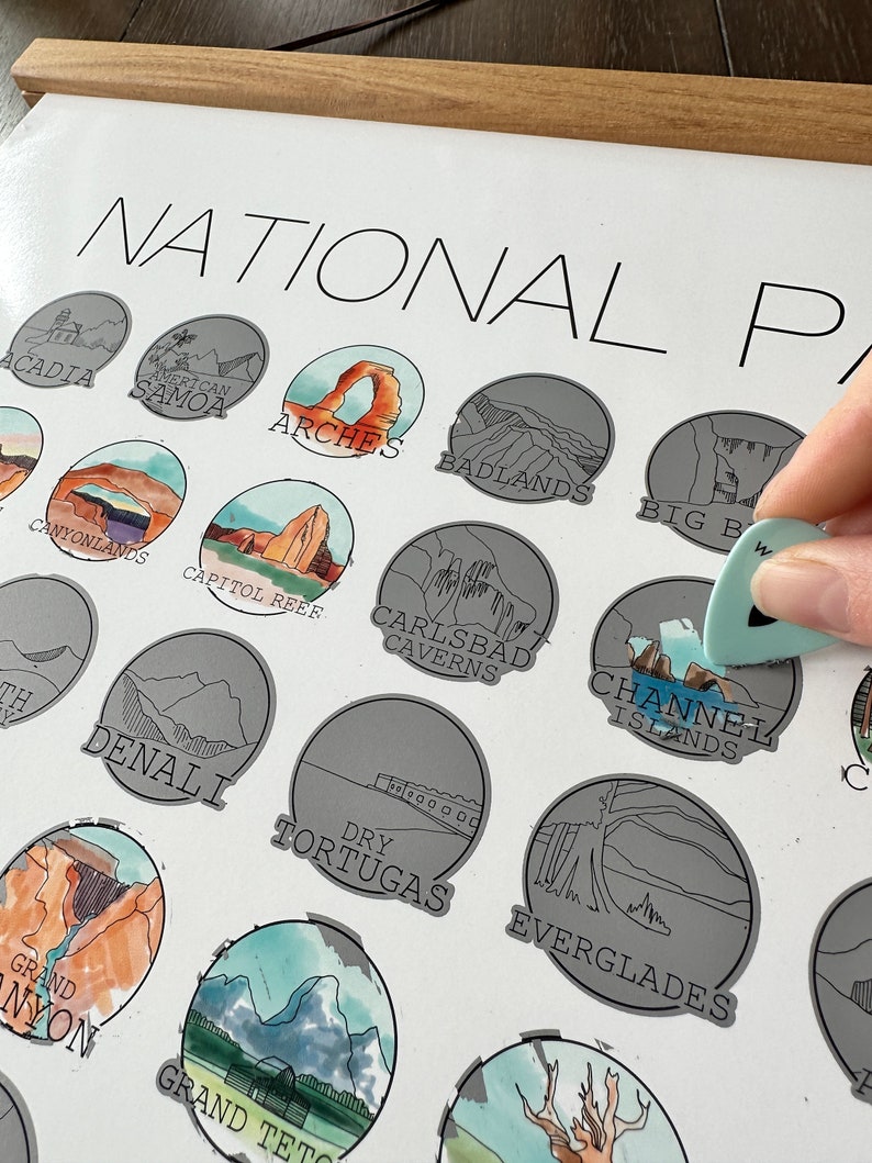 May include: A poster with a white background and the text "NATIONAL PARKS" at the top. The poster features a grid of illustrated national parks, each with a unique design and name. The parks include Acadia, American Samoa, Arches, Badlands, Big Bend, Canyonlands, Capitol Reef, Carlsbad Caverns, Channel Islands, Denali, Dry Tortugas, Everglades, Grand Canyon, and Grand Teton.