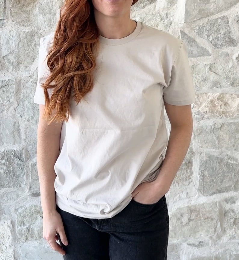 Puede incluir: Una camiseta gris claro de cuello redondo y mangas cortas.