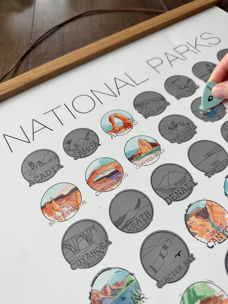 May include: A white poster with the title "National Parks" printed in black. The poster features a collection of illustrated national park logos, each with a unique design and color scheme. The logos are arranged in a circular pattern, with the names of the parks printed below each logo.