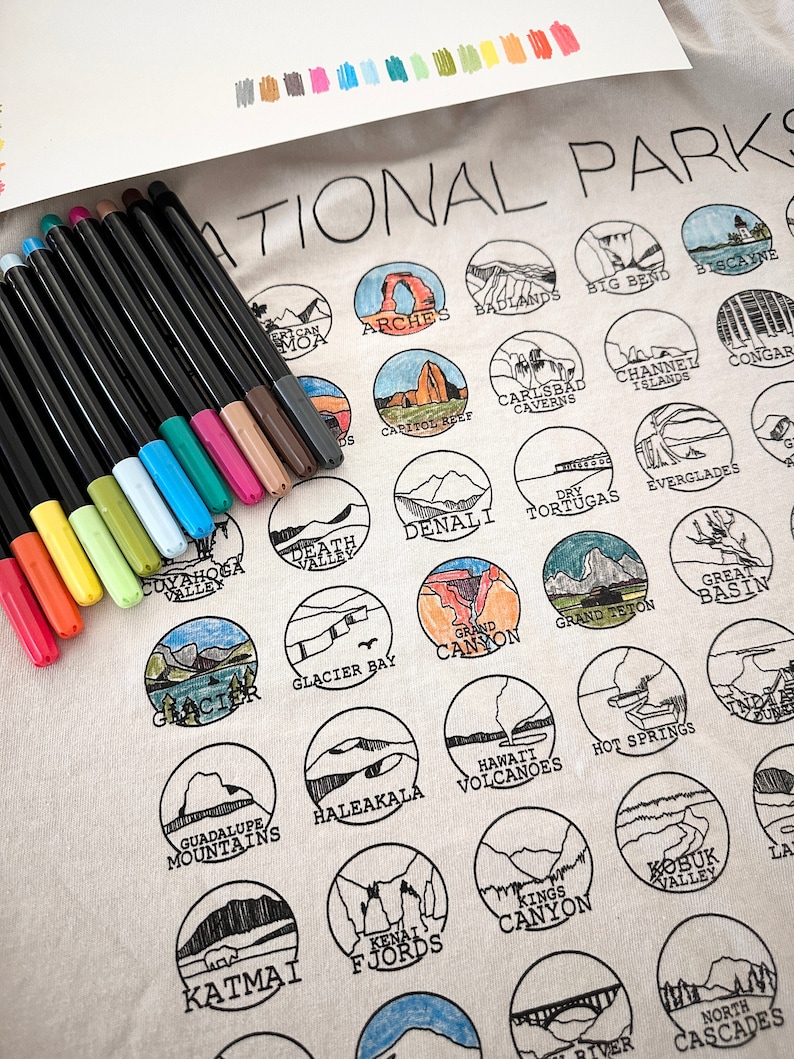 Puede incluir: Una bolsa de tela blanca con contornos negros de parques nacionales y sus nombres. La bolsa est&aacute; decorada con marcadores de colores.