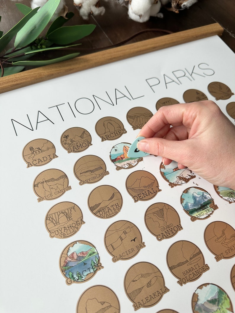 May include: A brown and white poster with the title "National Parks" and illustrations of different national parks in the United States. The poster is on a wooden frame.
