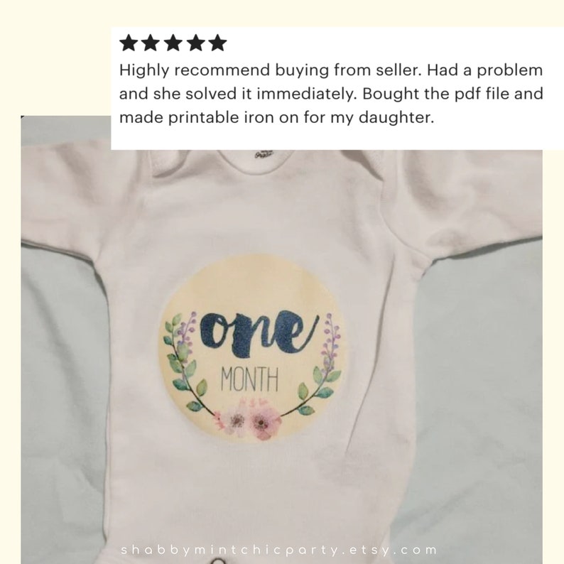 May include: A white onesie with a yellow circle featuring the word "one" in blue script and the words "MONTH" in black text. The circle is surrounded by a green wreath with pink flowers.