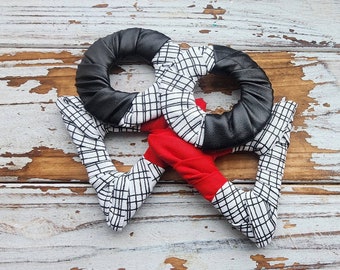 May include: Two black fabric rings with a white and black checkered pattern, tied together with a red fabric ring with a white and black checkered pattern.