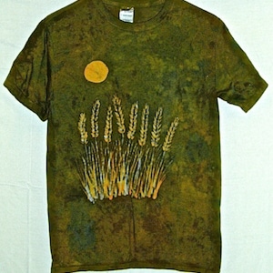 May include: A green t-shirt with a tie-dye pattern featuring a yellow sun and a graphic of wheat stalks.