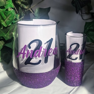 May include: Two purple glitter glasses with the number 21 and the name Andrea on them.