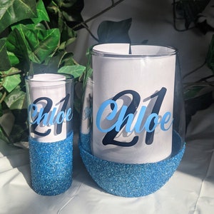 May include: Two blue glitter glasses with the name "Chloe" and the number "21" on them.