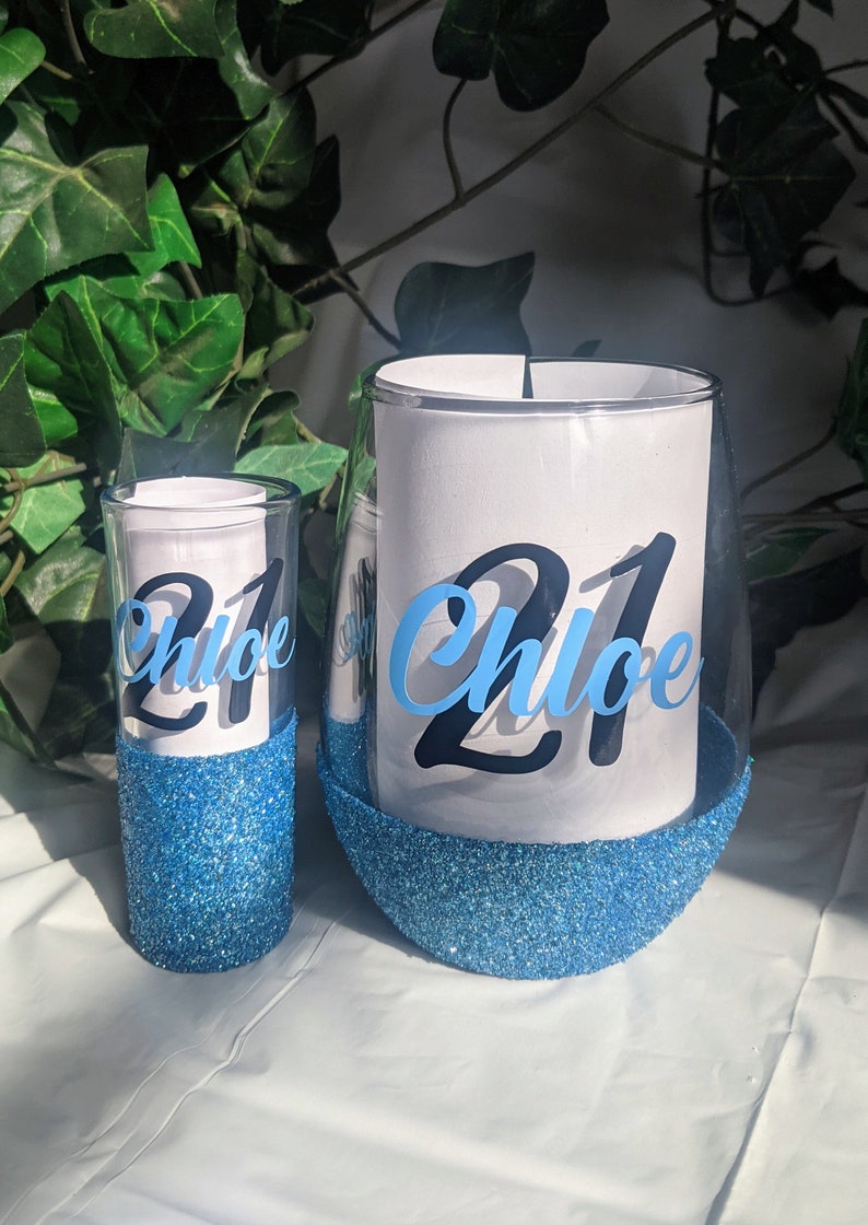 May include: Two blue glitter glasses with the name "Chloe" and the number "21" on them.
