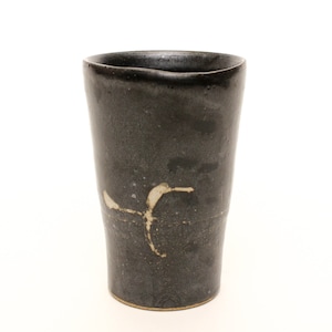 May include: A black ceramic cup with a white design. The cup has a slightly irregular shape and a textured surface.