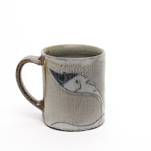May include: A ceramic mug with a textured, light gray finish and a dark brown handle. A black and white illustration of a bird is on the side. The mug is suitable for hot or cold beverages.