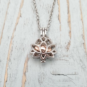 Op de afbeelding: Zilveren ketting met een roségouden lotusbloem bedel. De bedel is open en heeft een kleine ronde ruimte binnenin.
