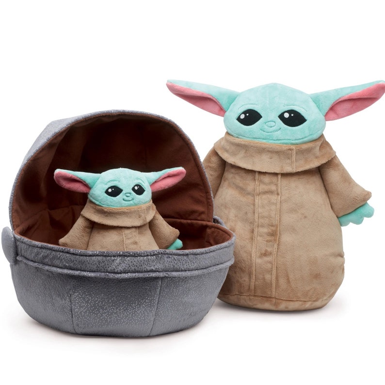 May include: Two plush toys of the character "The Child" from the Star Wars series "The Mandalorian". The larger plush toy is standing and the smaller plush toy is sitting inside a grey egg-shaped pod.