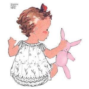May include: A vintage Simplicity sewing pattern for a baby girl's dress and diaper cover. The pattern number is 1813. The illustration shows a baby girl wearing the dress and diaper cover, holding a pink bunny toy.