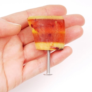 Puede incluir: Un pomo de armario de resina rojo, amarillo y naranja con un tornillo plateado.