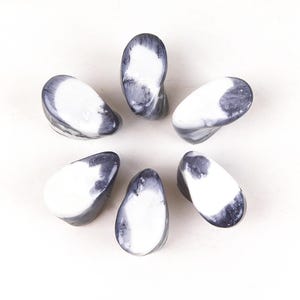 Peut inclure: Six pierres lisses en forme de goutte d'eau disposées en cercle. Chaque pierre a une base blanche avec des marbrures grises et noires. Les pierres sont présentées sur un fond blanc.