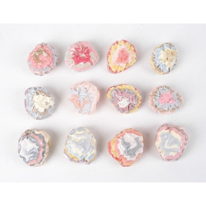 Peut inclure: Douze ornements en céramique faits à la main en forme de fleur. Chaque ornement est unique avec une combinaison de couleurs différente de rose, jaune, bleu et gris.