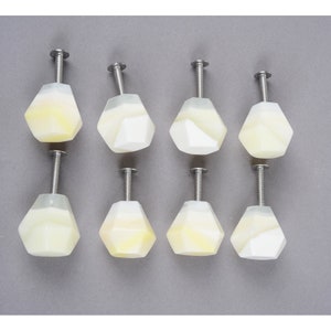 May include: Eight white and yellow geometric cabinet knobs with silver screws.
