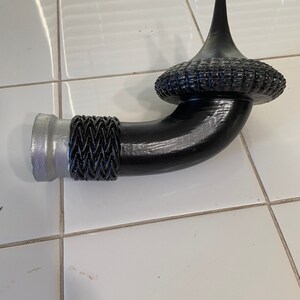 May include: A black metal pipe with a decorative finial. The pipe has a silver metal base and a black braided design.