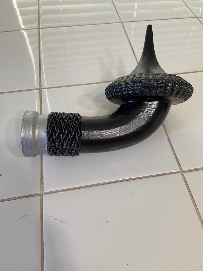 May include: A black metal pipe with a decorative finial. The pipe has a silver metal base and a black braided design.