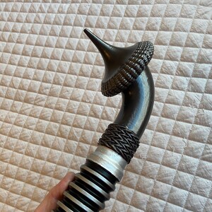 May include: A black lightsaber with a silver and black ribbed handle and a black, spiky, cone-shaped hilt.