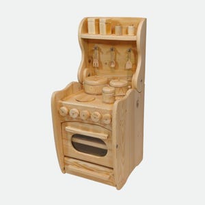 Könnte beinhalten: Spielzeugküche aus Holz mit natürlichem Finish. Das Set enthält einen Herd, einen Backofen und ein Regal mit Miniaturtöpfen, Utensilien und Gewürzgläsern. Der Backofen hat ein klares Fenster und eine Schublade darunter.