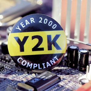Peut inclure: Un bouton noir et jaune avec le texte "YEAR 2000 Y2K COMPLIANT" sur une carte mère d'ordinateur.
