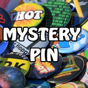 Può includere: Una collezione di spille da balia colorate e diverse con vari disegni, tra cui una lumaca, un cactus, un computer, un'ape e il testo "HOT" e "Y2K". Il testo "MYSTERY PIN" è scritto in grandi caratteri grassetto al centro dell'immagine.
