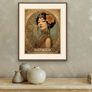 May include: A framed art print featuring a woman with dark hair and a floral headpiece. The woman is wearing a gold and brown patterned dress. The print is in an Art Nouveau style and includes the text "TrauCrejo".