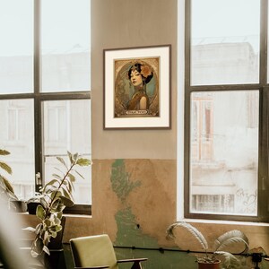 May include: A framed art print featuring a woman in a vintage style illustration. The woman is wearing a blue and gold dress with a flower in her hair. The print has a gold background with ornate details and the word "TRUCHTER" at the bottom.