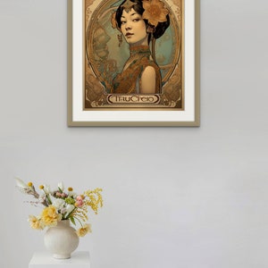 May include: A framed art print featuring a woman with a flower in her hair. The print is in an Art Nouveau style and has a gold frame. The text "Tracfeio" is at the bottom of the print.