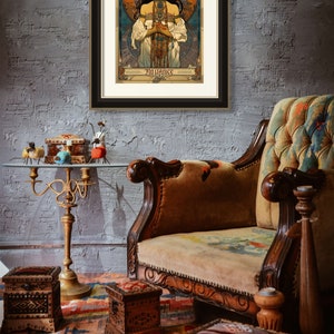 May include: A framed vintage poster with a woman in a flowing white dress and a crown of flowers. The poster is titled "La Villance" and is surrounded by a gold frame.
