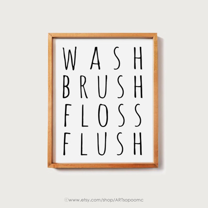 Peut inclure: Impression encadr&eacute;e avec les mots "WASH BRUSH FLOSS FLUSH" en noir, police sans-serif. L'impression est sur fond blanc et encadr&eacute;e dans un cadre en bois brun clair. L'adresse du site web est au bas du cadre.