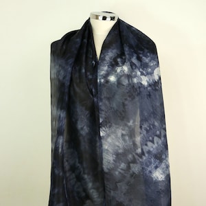 Op de afbeelding: Een doorschijnende zwart-witte tie-dye sjaal met een draaiend patroon.
