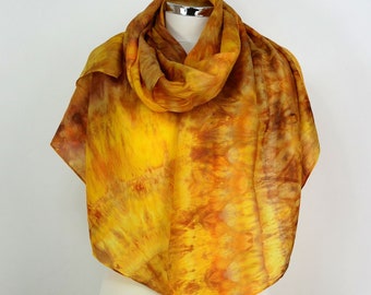 Może przedstawiać: Żółto-pomarańczowy jedwabny szal z wzorem tie-dye. Szal jest drapowany na białym manekinie.