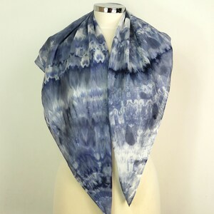 May include: A blue and white silk scarf with a tie-dye pattern. The scarf is folded in half and draped over a mannequin.