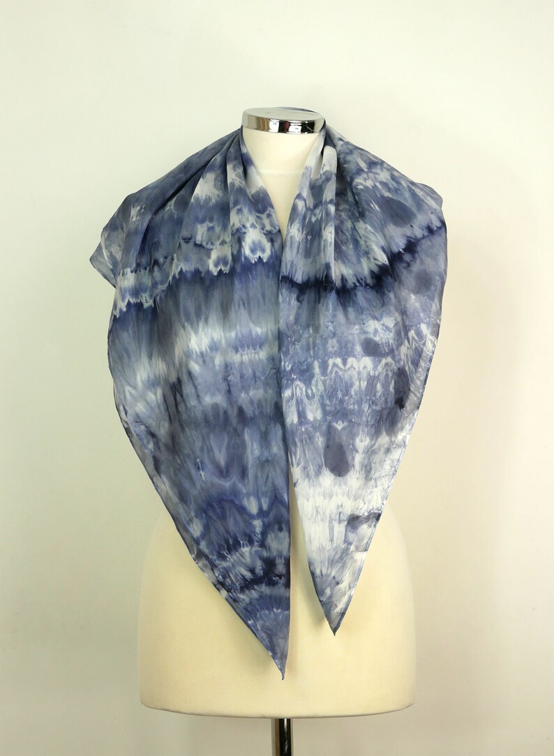 May include: A blue and white silk scarf with a tie-dye pattern. The scarf is folded in half and draped over a mannequin.