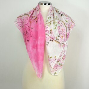 May include: A pink and white silk scarf with a floral pattern. The scarf is folded and displayed on a white mannequin.