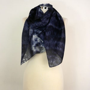 Op de afbeelding: Een marineblauwe en witte tie-dye zijden sjaal gedrapeerd op een wit mannequin.