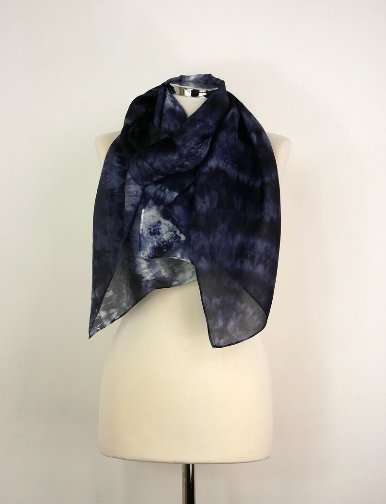 Op de afbeelding: Een marineblauwe en witte tie-dye zijden sjaal gedrapeerd op een wit mannequin.