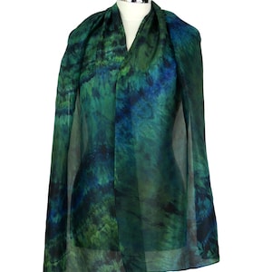 May include: A rectangular scarf featuring a tie-dye pattern in shades of forest green, emerald, and deep navy blue. The fabric is semi-sheer and lightweight, draped over a mannequin to display the blended colour transitions and organic textures.