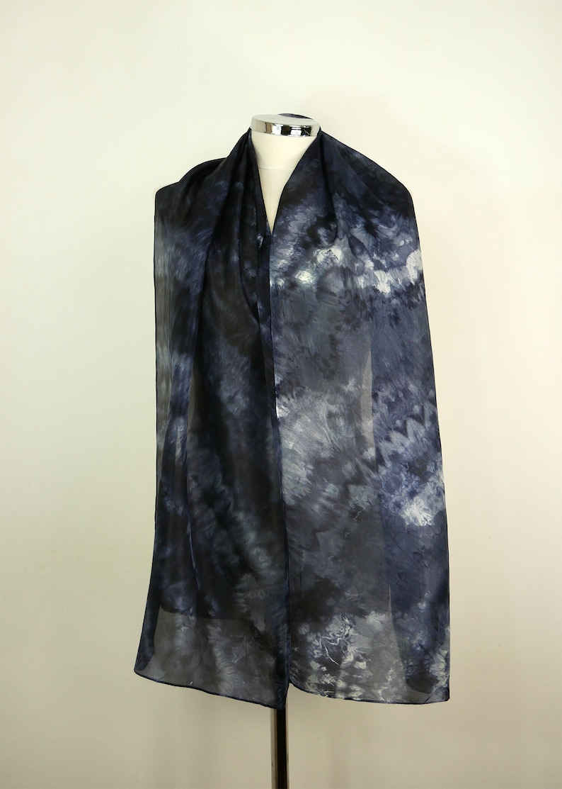 Op de afbeelding: Een doorschijnende zwart-witte tie-dye sjaal met een draaiend patroon.