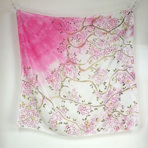 May include: A white silk scarf with a pink and green floral design. The design features a tree with branches and leaves, and pink flowers.