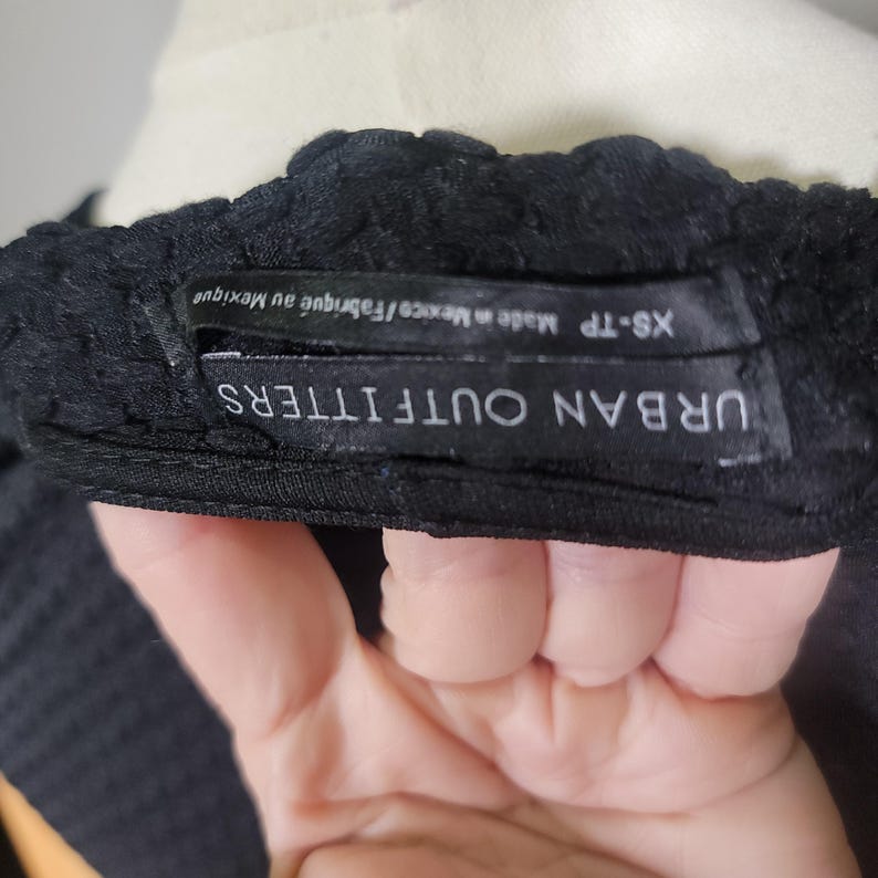 May include: Black Urban Outfitters top with a tag that reads "XS-TP Made in Mexico/Fabrique au Mexique"